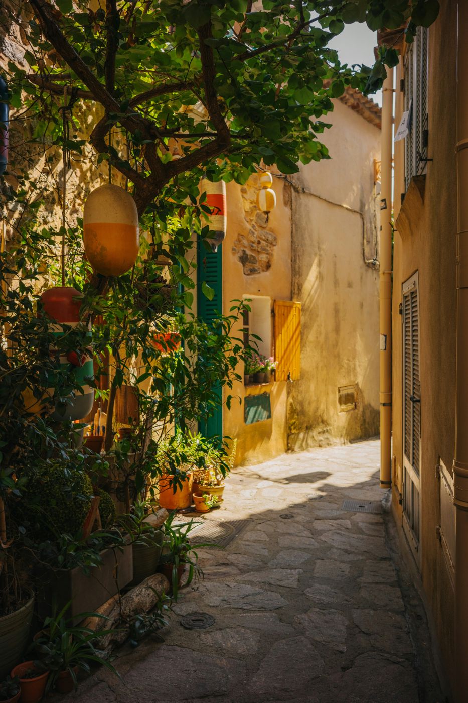 A narrow stone alleyway hung with fishing buoys